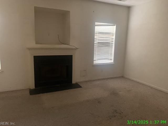 unfurnished living room with a fireplace with flush hearth, carpet, visible vents, and baseboards