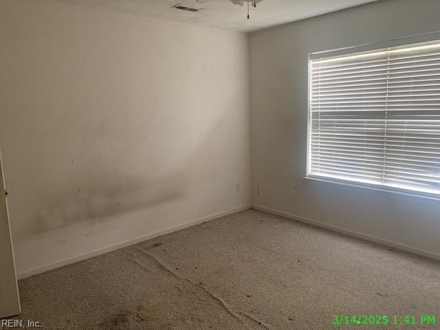 carpeted empty room featuring a healthy amount of sunlight, visible vents, and baseboards