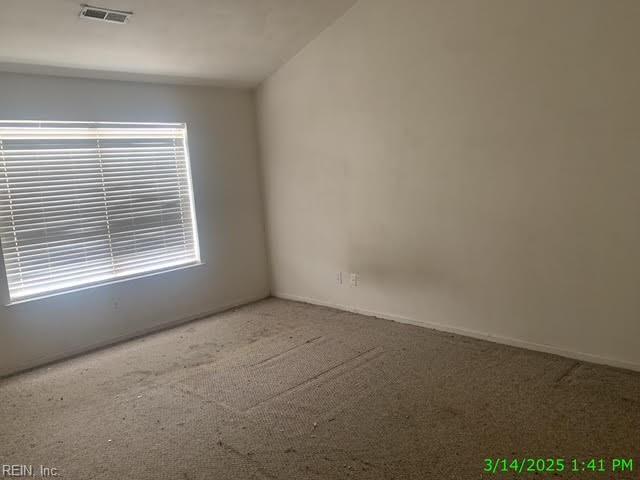 carpeted empty room featuring visible vents