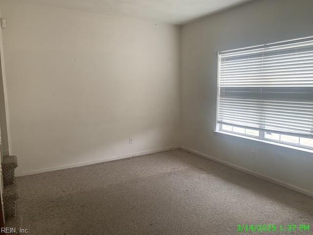 carpeted spare room featuring baseboards