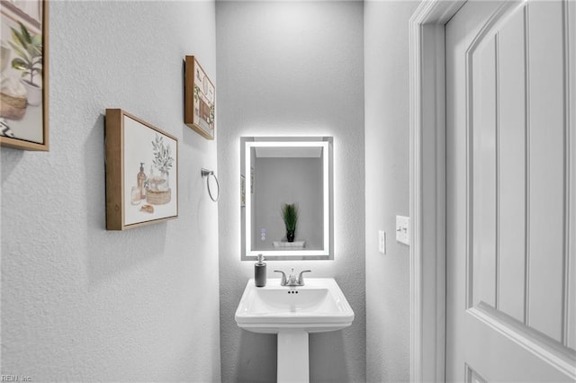 bathroom featuring a textured wall and a sink