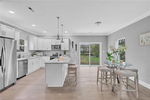 kitchen featuring stainless steel appliances, plenty of natural light, light wood-style floors, and a center island