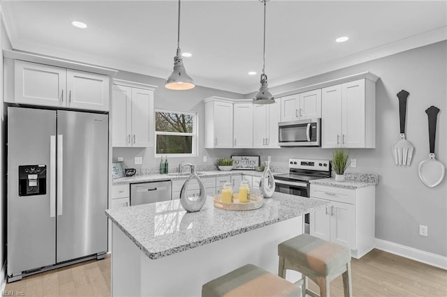 kitchen with a kitchen bar, light wood-style flooring, a sink, stainless steel appliances, and hanging light fixtures