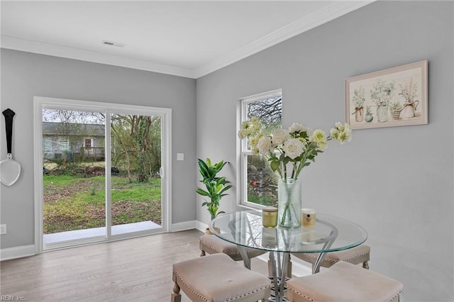 dining room featuring visible vents, ornamental molding, baseboards, and wood finished floors