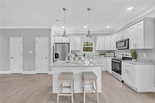 kitchen with stainless steel appliances, ornamental molding, a center island, and white cabinetry