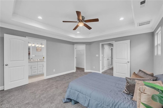 bedroom featuring a tray ceiling, light colored carpet, and visible vents