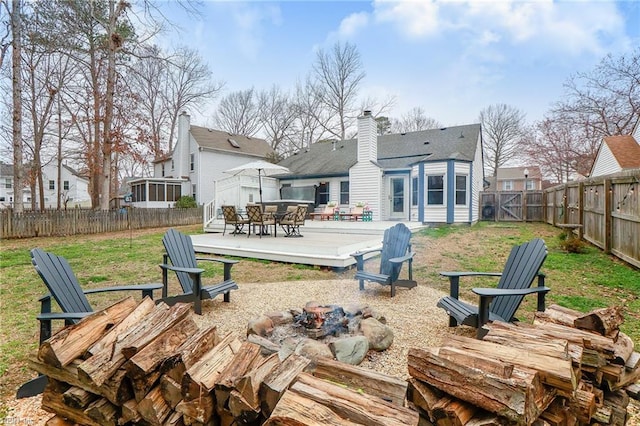 rear view of house featuring a wooden deck, a residential view, a fire pit, and a fenced backyard