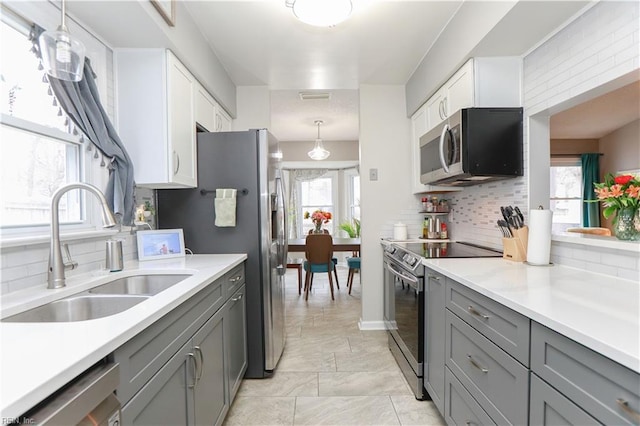 kitchen with visible vents, gray cabinetry, light countertops, appliances with stainless steel finishes, and a sink