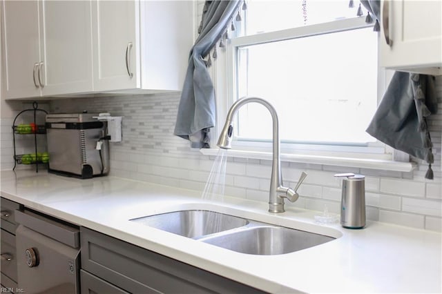 kitchen featuring light countertops, white cabinets, a healthy amount of sunlight, and a sink