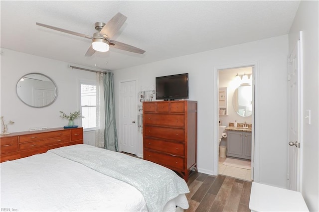 bedroom featuring a sink, connected bathroom, a closet, ceiling fan, and dark wood-style flooring