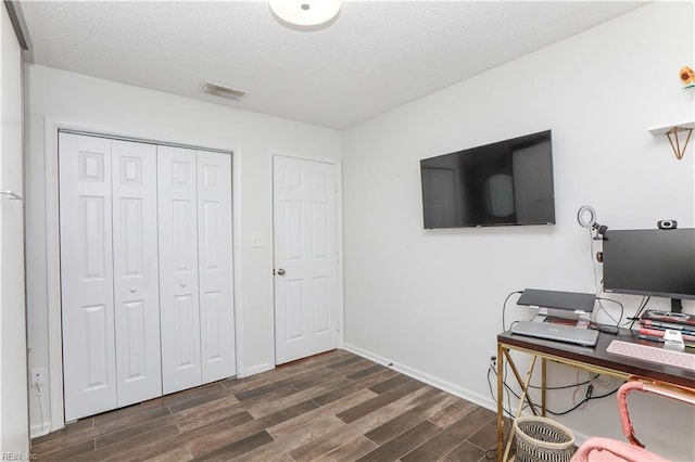 office area featuring baseboards, visible vents, dark wood-style flooring, and a textured ceiling