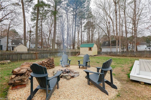 view of yard featuring a storage unit, a fenced backyard, an outdoor fire pit, a residential view, and an outdoor structure