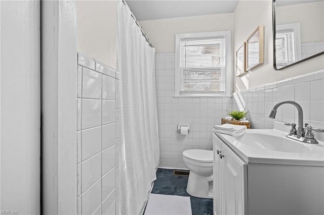 full bath featuring vanity, tile walls, toilet, and visible vents