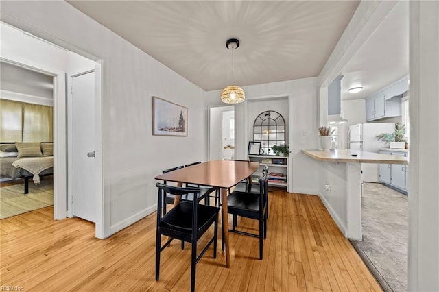 dining area with baseboards and light wood finished floors