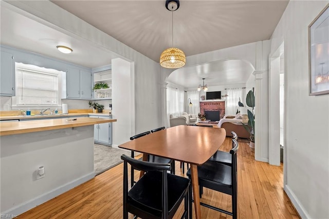 dining space with baseboards, light wood-style floors, arched walkways, and a chandelier