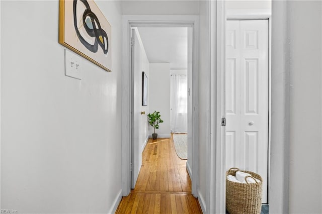 corridor featuring light wood-type flooring and baseboards