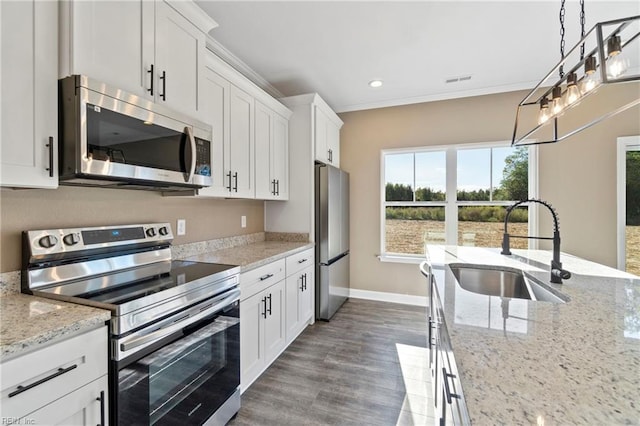 kitchen featuring white cabinets, stainless steel appliances, crown molding, and a sink