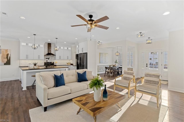 living area with dark wood finished floors, recessed lighting, crown molding, and ceiling fan