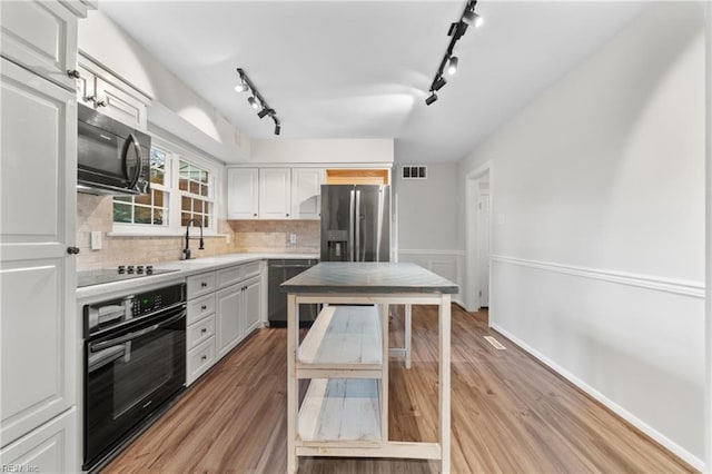 kitchen featuring visible vents, black appliances, light wood-style flooring, a sink, and light countertops