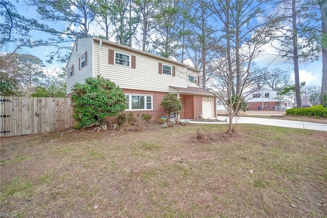 view of front facade featuring brick siding, an attached garage, fence, a front yard, and driveway