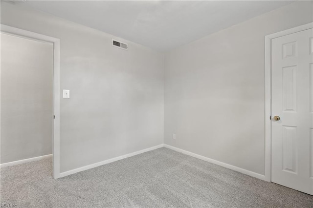 carpeted empty room featuring visible vents and baseboards