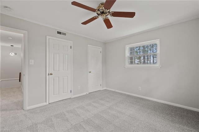 unfurnished bedroom featuring crown molding, carpet flooring, baseboards, and visible vents