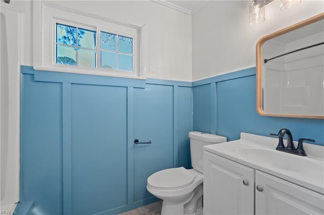 bathroom with walk in shower, toilet, ornamental molding, wainscoting, and vanity