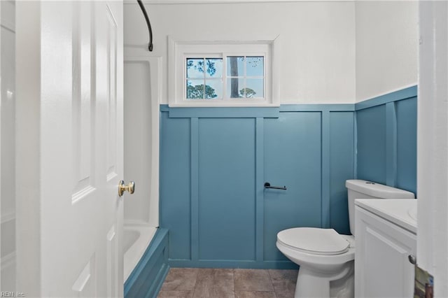 full bathroom with washtub / shower combination, toilet, vanity, and a decorative wall