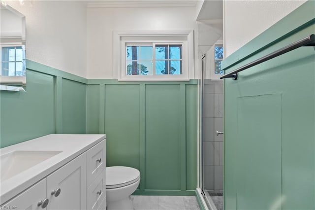 full bath with toilet, wainscoting, a stall shower, a decorative wall, and vanity