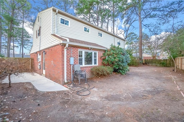 rear view of property featuring a patio area, brick siding, and fence