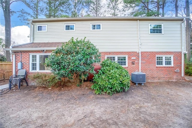 rear view of property with brick siding, cooling unit, and fence