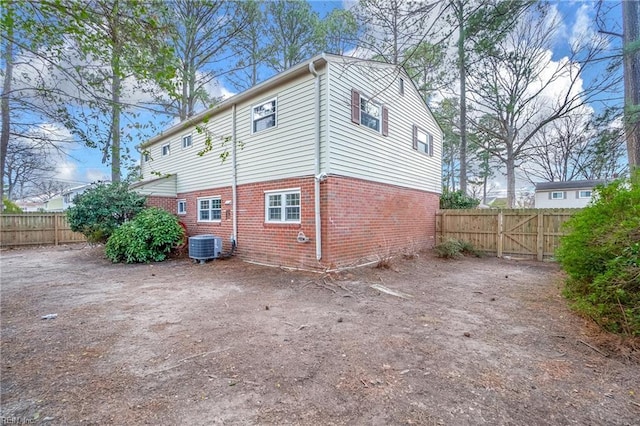 view of side of property featuring brick siding, central air condition unit, and fence