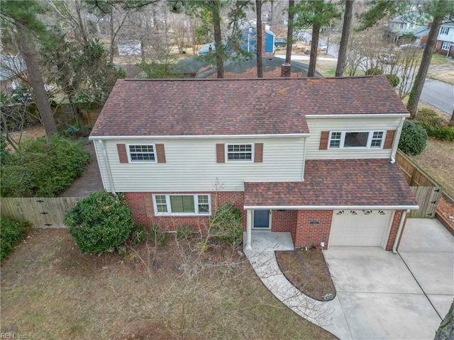 traditional home with roof with shingles, concrete driveway, an attached garage, and fence