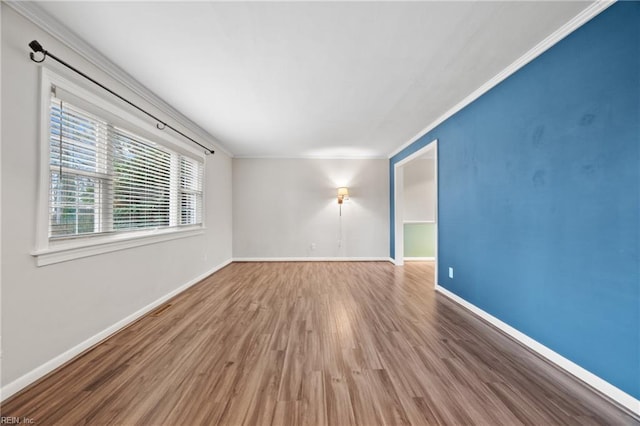 unfurnished room with baseboards, wood finished floors, and ornamental molding