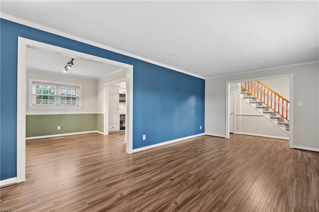 unfurnished living room featuring baseboards, wood finished floors, stairs, and crown molding