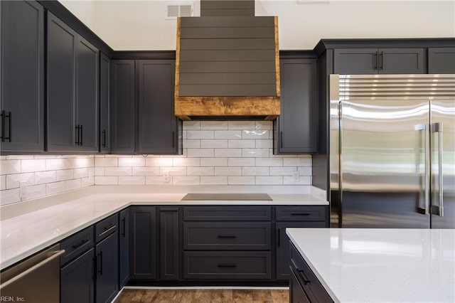 kitchen with visible vents, light stone counters, tasteful backsplash, wood finished floors, and appliances with stainless steel finishes