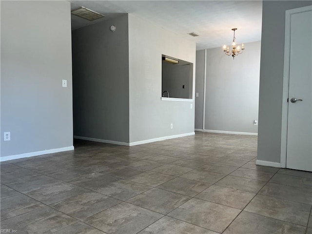 spare room featuring baseboards, visible vents, and an inviting chandelier