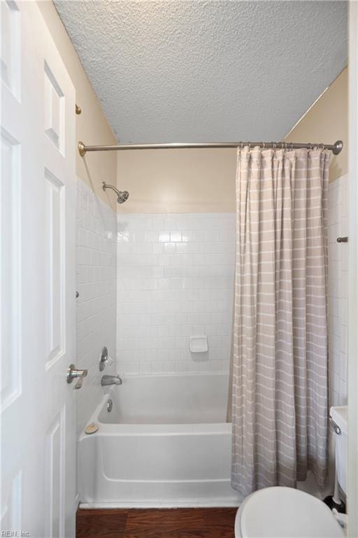 bathroom with toilet, wood finished floors, shower / tub combo with curtain, and a textured ceiling