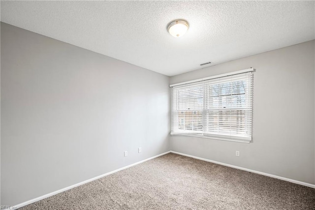 carpeted spare room featuring baseboards, visible vents, and a textured ceiling