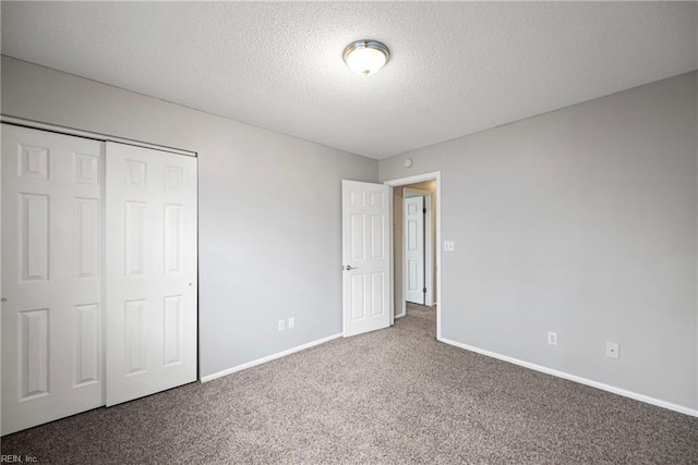 unfurnished bedroom featuring baseboards, a closet, carpet floors, and a textured ceiling