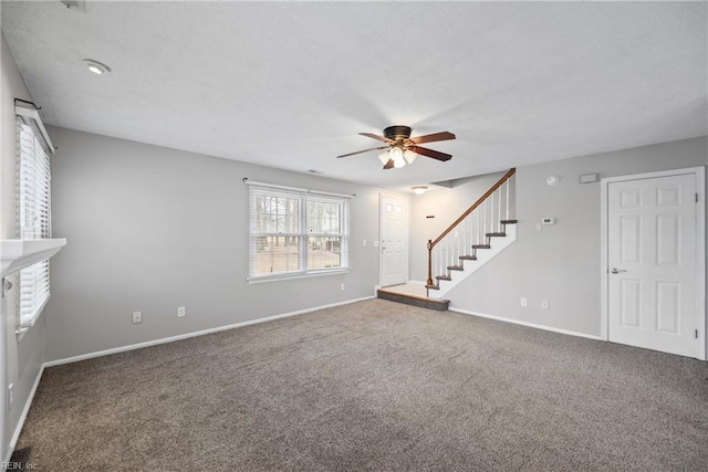 unfurnished living room featuring a textured ceiling, stairway, carpet flooring, and ceiling fan