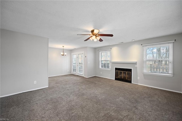 unfurnished living room with baseboards, carpet flooring, ceiling fan with notable chandelier, a glass covered fireplace, and a textured ceiling