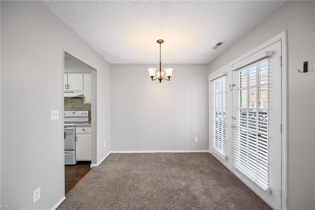 unfurnished dining area featuring an inviting chandelier, visible vents, dark carpet, and a textured ceiling