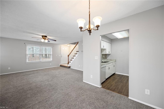 unfurnished living room with baseboards, stairs, a textured ceiling, ceiling fan with notable chandelier, and dark carpet