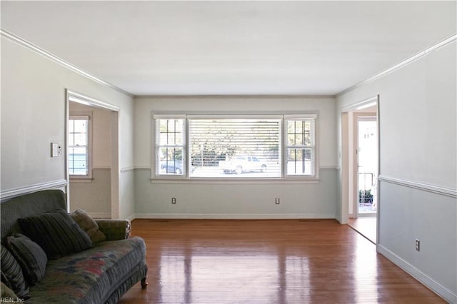 living area featuring crown molding, baseboards, and wood finished floors