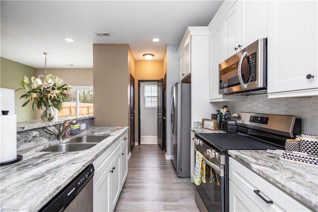 kitchen featuring tasteful backsplash, visible vents, appliances with stainless steel finishes, white cabinetry, and a sink