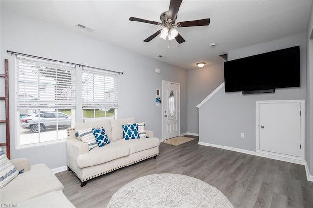 living room featuring visible vents, baseboards, ceiling fan, and wood finished floors