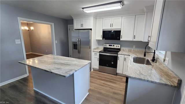 kitchen featuring white cabinets, appliances with stainless steel finishes, light wood-style floors, and a sink