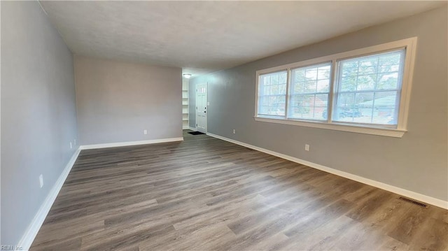 unfurnished room featuring visible vents, baseboards, and wood finished floors