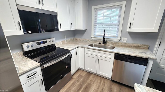 kitchen featuring appliances with stainless steel finishes, white cabinetry, and a sink